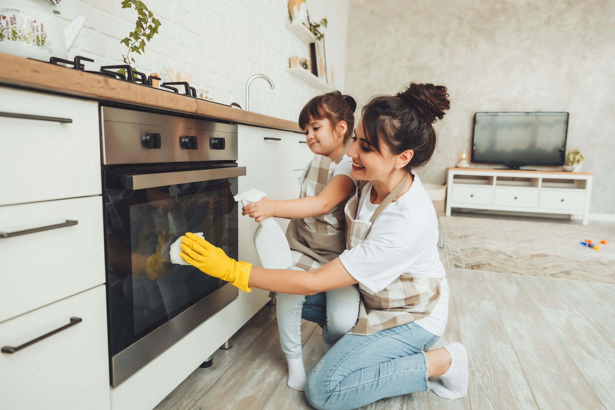 A little girl and her mother are cleaning the kitchen.woman and child wipe the oven in the kitchen